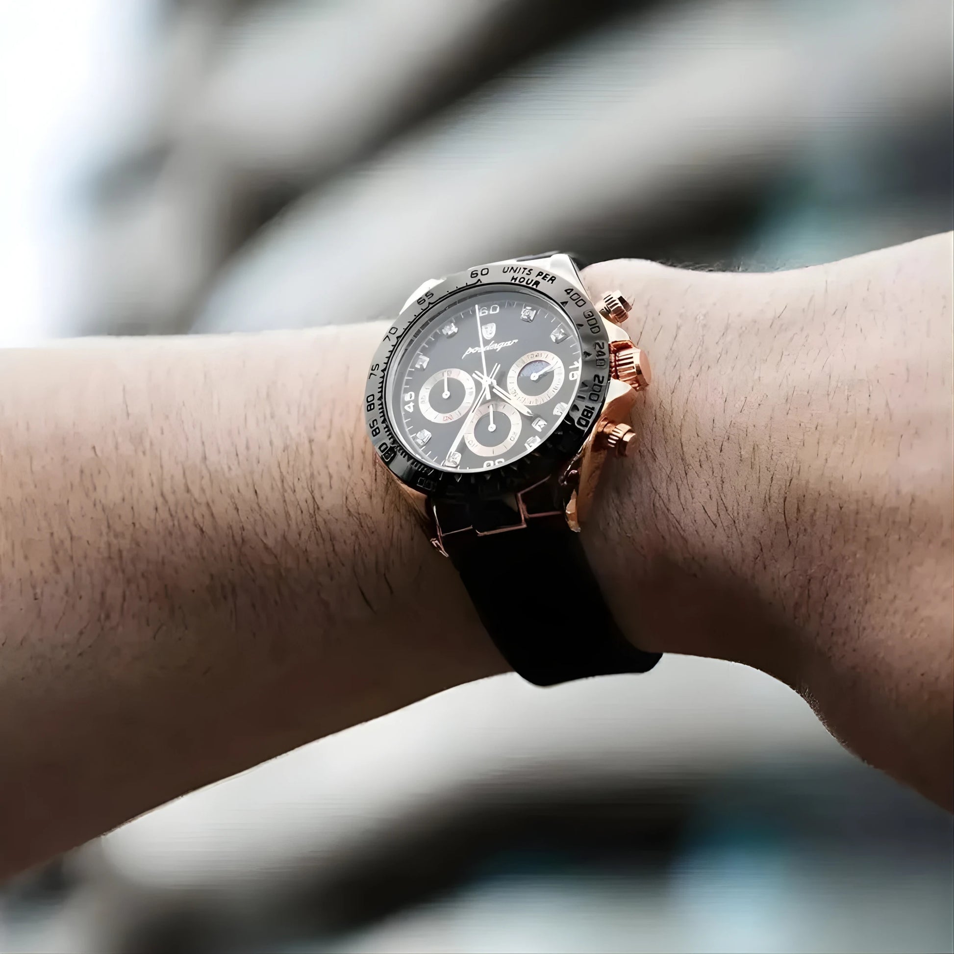 Luxury watch with black dial and rose gold case on a wrist against a blurred background