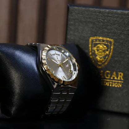 Luxury watch with gold and silver accents on a dark surface, next to a Jaguar Land Rover box.