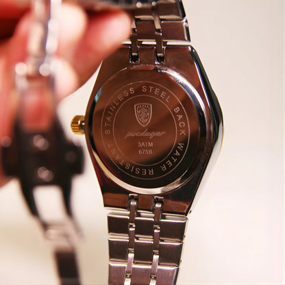 Close-up of a silver watch with brand logo and text on the back, blurred background