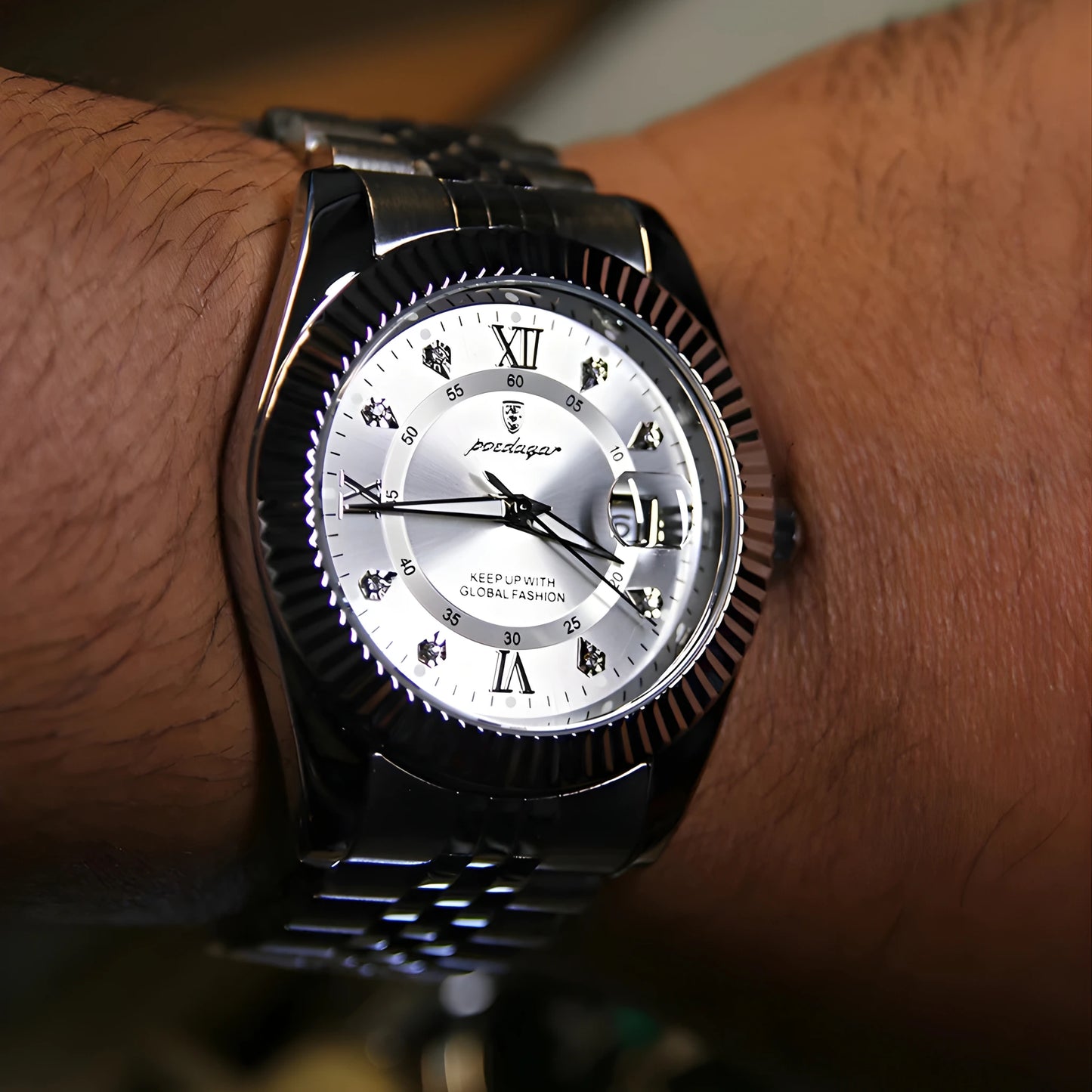 Silver wristwatch with a detailed face on a person's wrist.
