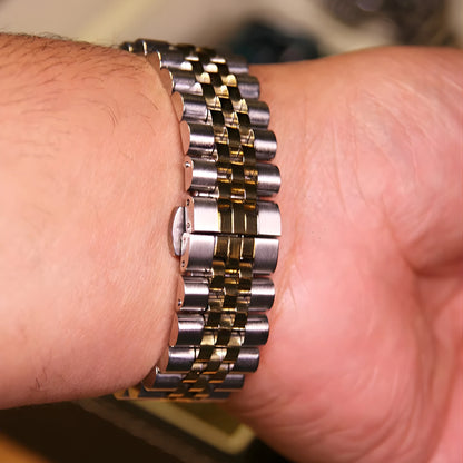 Close-up of a person's wrist wearing a silver and gold watch.